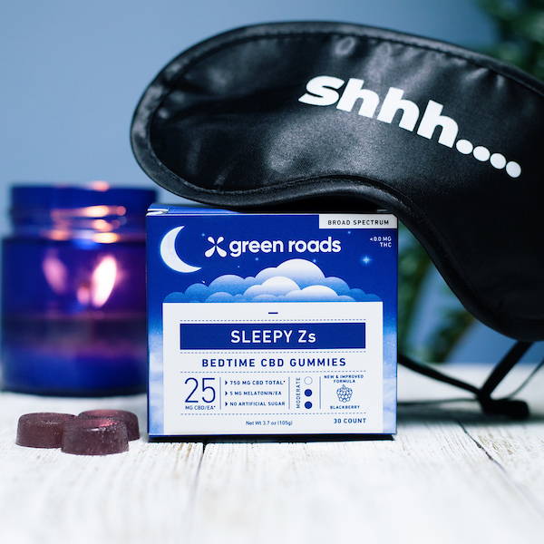 Green Roads CBD Sleepy Zs Gummies on night table with sleep mask