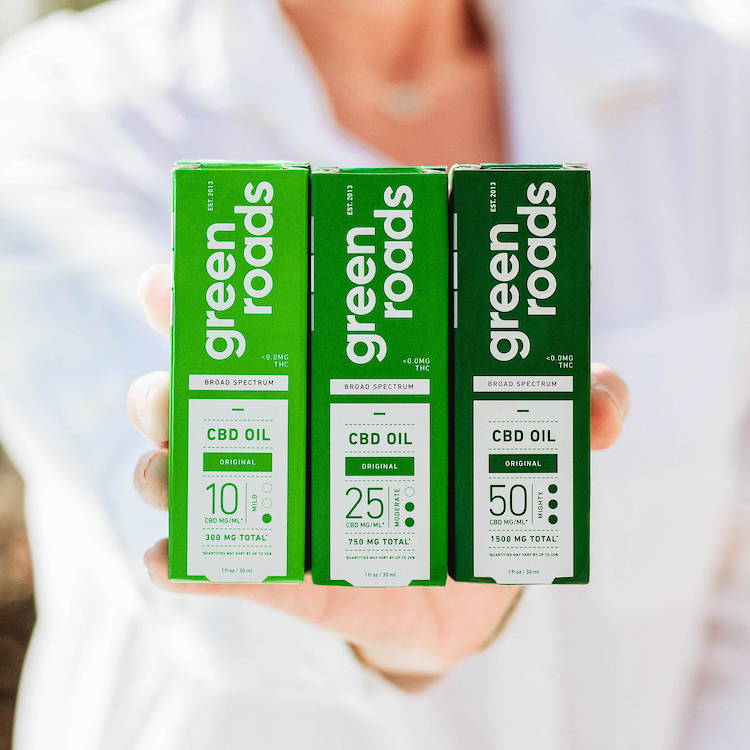 Woman holds CBD oil line from Green Roads CBD